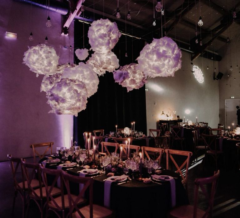 Incredible purple hanging light installation in the shape of clouds over the wedding table