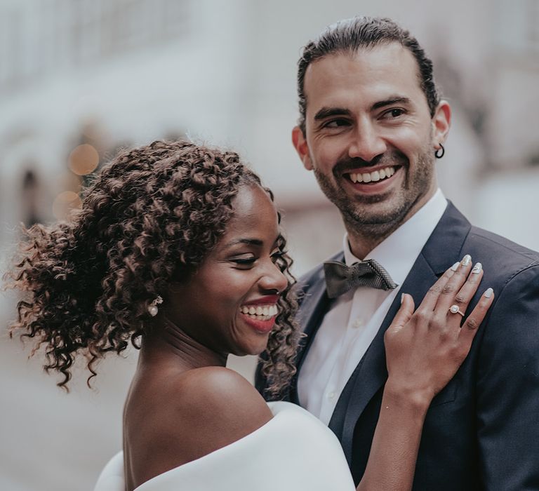 Bride & groom laugh as bride places hand on grooms shoulder