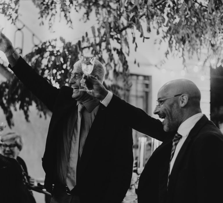 Black & white image of wedding guest cheers'ing during wedding reception