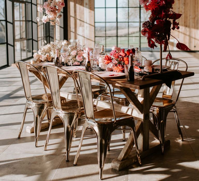 Intimate wedding tablescape with red and pink flowers, metal chairs and copper installation 