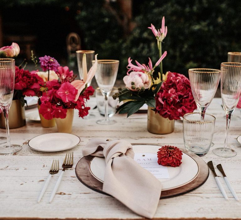 Romantic pink tablescape with pink floral centrepieces, gold rimmed glassware and white tableware