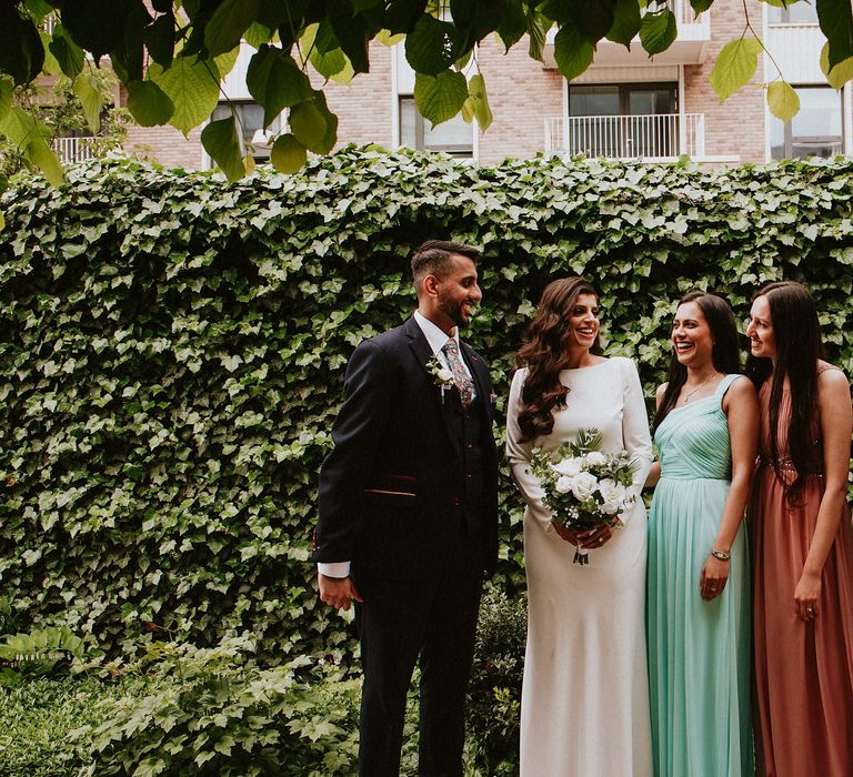 Bride and groom with their bridesmaids in different coloured dresses 