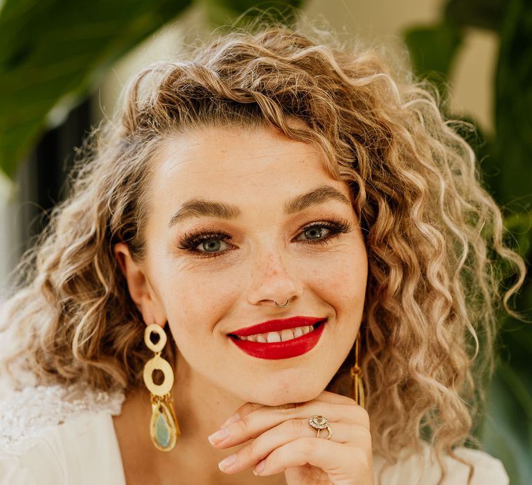 Beautiful blonde naturally curly haired bride with bright red lipstick and brown shimmering eyeshadow at fiesta theme wedding 