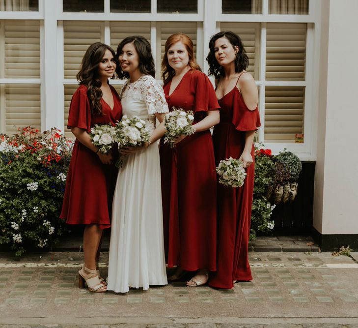 Bride in a laser cut lace wedding dress standing with her three bridesmaids in different style ReWritten bridesmaid dresses 