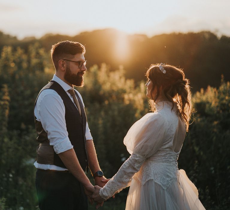 Bride & groom hold hands on their wedding day as the sun goes down