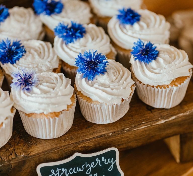 Strawberry and vanilla cupcakes complete with blue floral decoration 