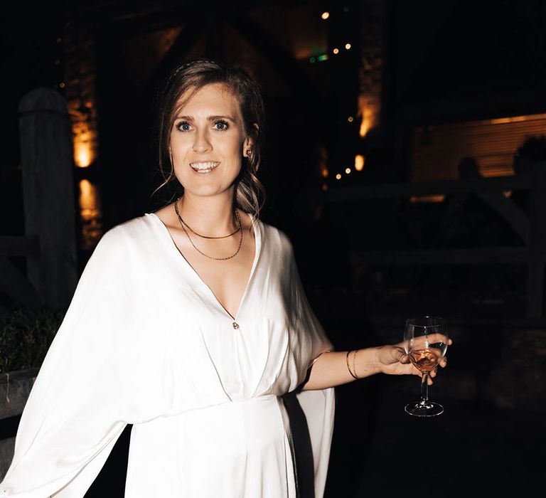 Brown haired bride carries wine glass during wedding reception