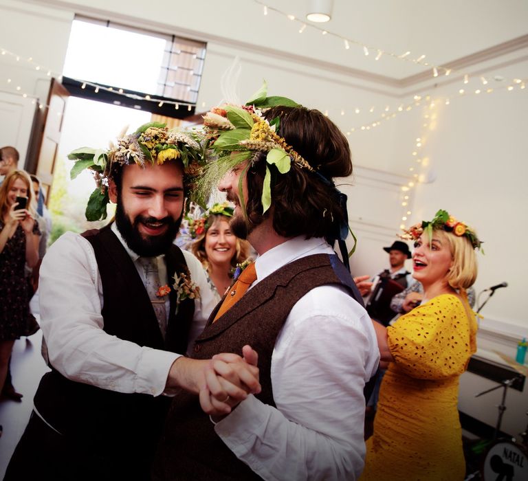 Grooms smile and dance with one another on their wedding day during reception