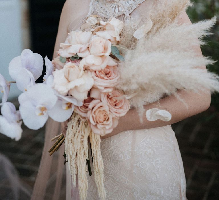 Destination wedding with bride in a high neck lace wedding dress and dark lipstick holding a pampas grass and orchid wedding bouquet 