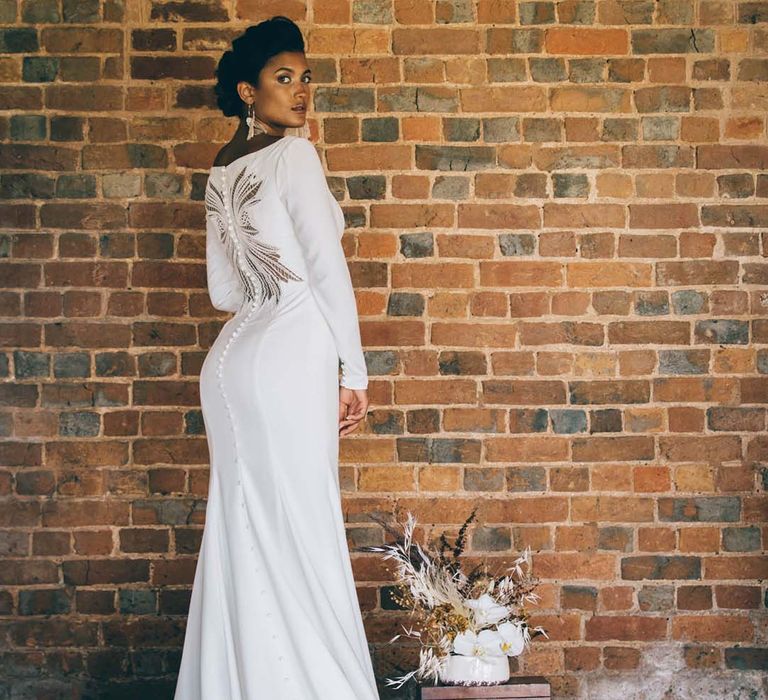 Bride in a fitted wedding dress with buttons and pattern on the back 