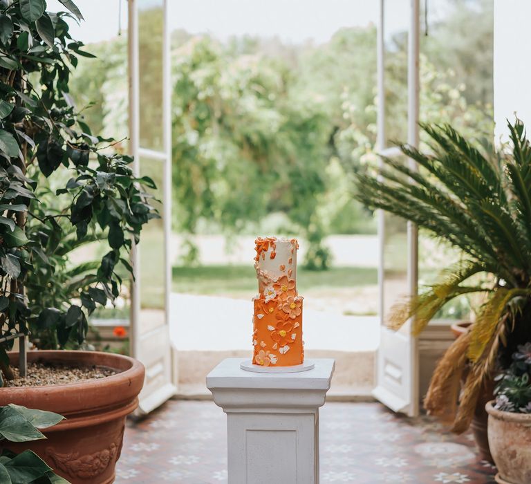 Two tier orange ombre buttercream wedding cake with petal decor in and orangery