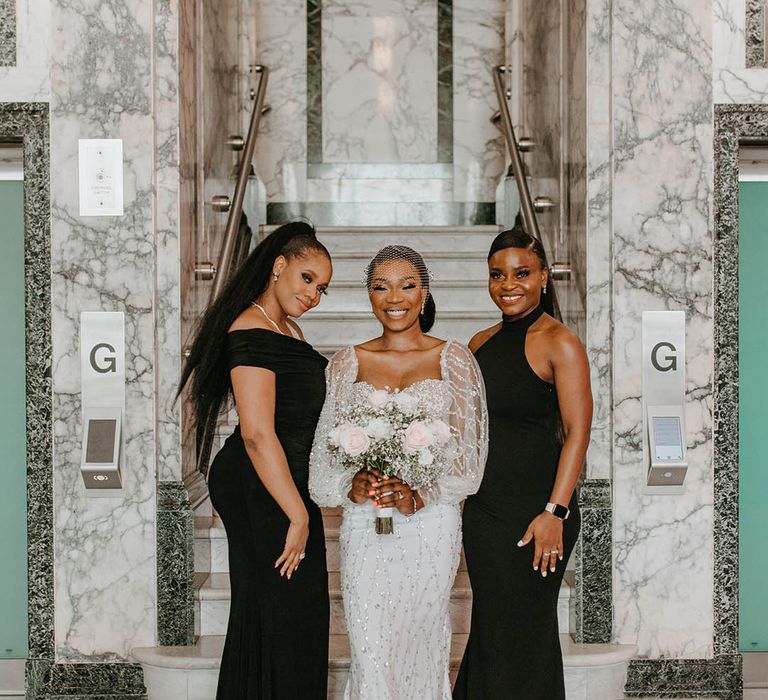 Bride stands with her bridesmaids who wear sleek black dresses