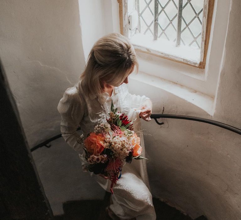 Bride walks up stairs clutching bouquet