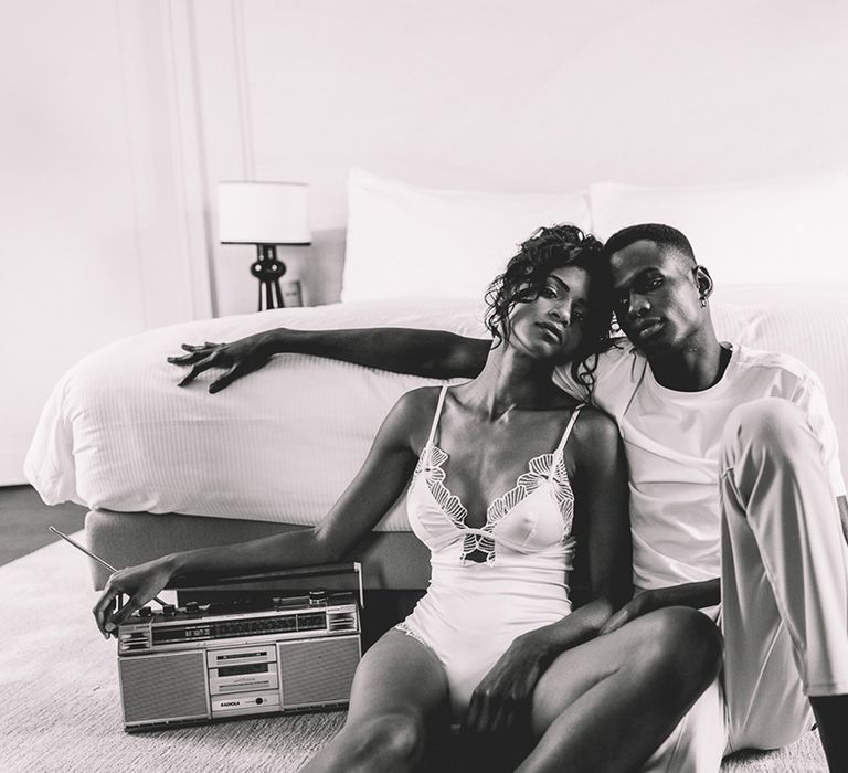 Black groom in a white cotton t-shirt embracing his South Asian bride in a satin and lace all in one on the wedding morning of their Paris elopement 