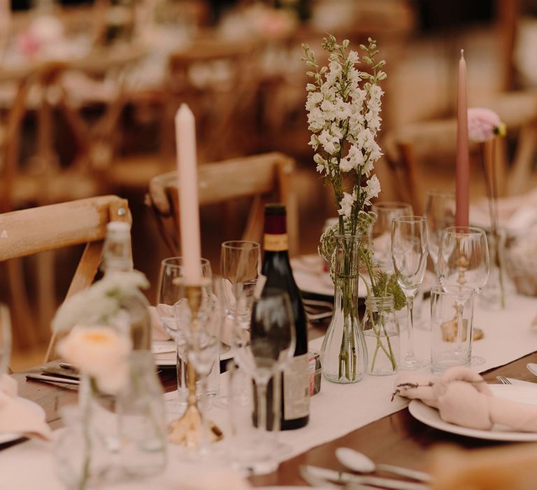 Pink candles and blush flowers decorated wooden tables