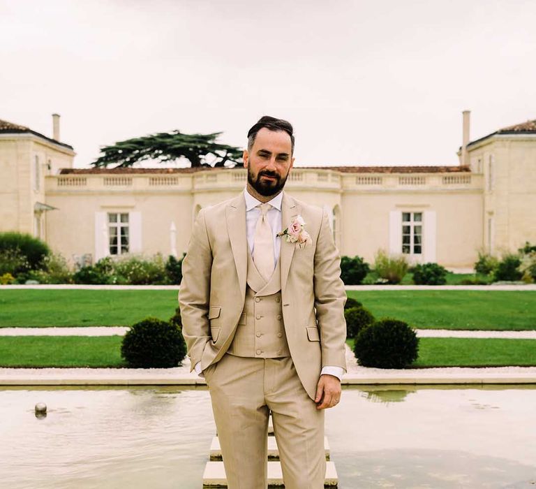 Groom wears beige suit on his wedding day outdoors