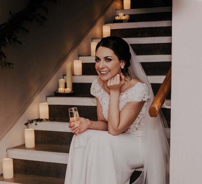 Bride sits on staircase on her wedding day