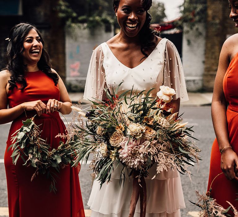 Beautiful Black bride in a bridal separates with layered skirt and pearl top holding an oversized wedding bouquet