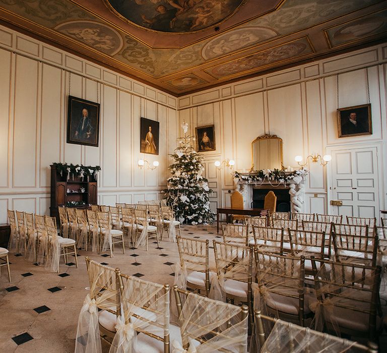 Gosfield Hall wedding venue complete with Christmas decor and chairs finished with gold chiffon bows