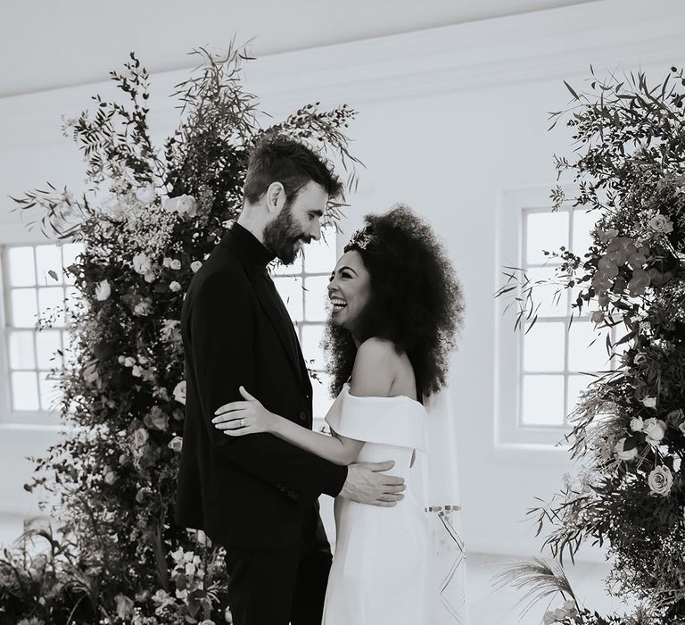 Black bride with afro hair in an off the shoulder wedding dress and appliqué patterned wedding veil 