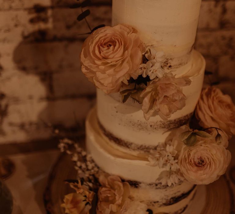 Semi-naked three tier white frosted wedding cake with pink and whit flower decorations and wooden heart cake topper with personalised details 