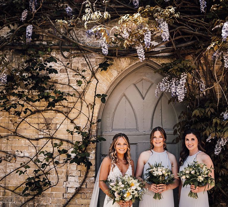 Bride in lace wedding dress with detachable tulle wings and bridesmaids in pleated halter neck grey dresses 