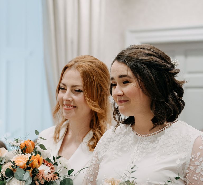 Brides look lovingly alongside one another during wedding ceremony