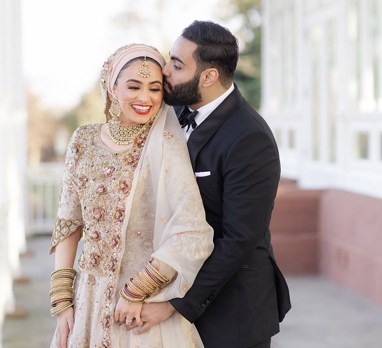 Groom wears black tie and kisses brides forehead after Walima 