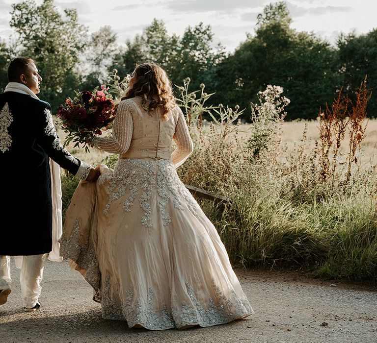 Bride walks with her groom who holds her lengha 