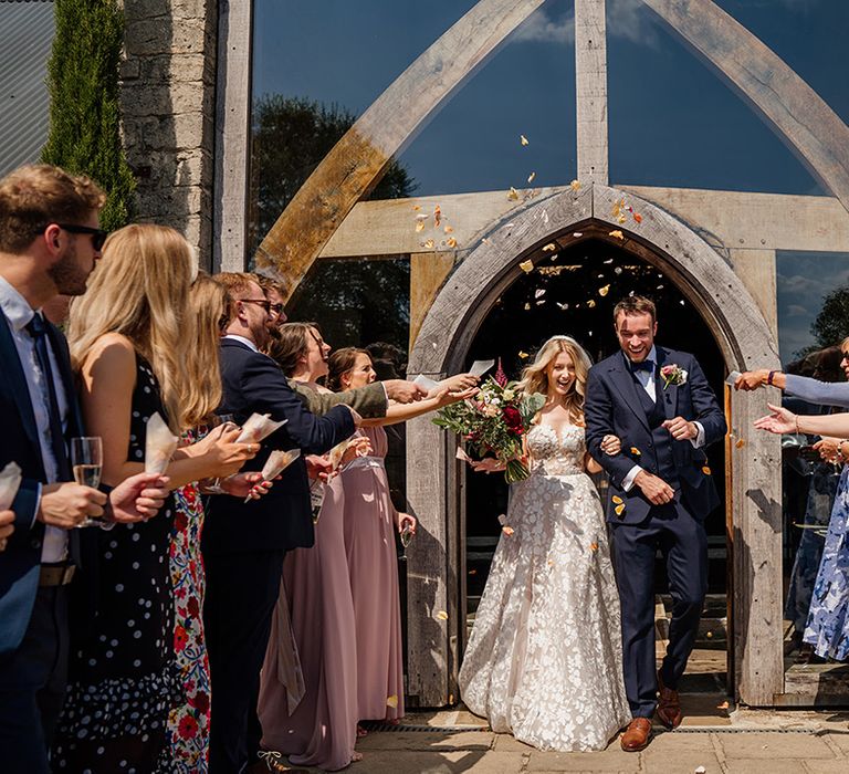 Bride and groom exit their wedding ceremony to rose petal confetti 