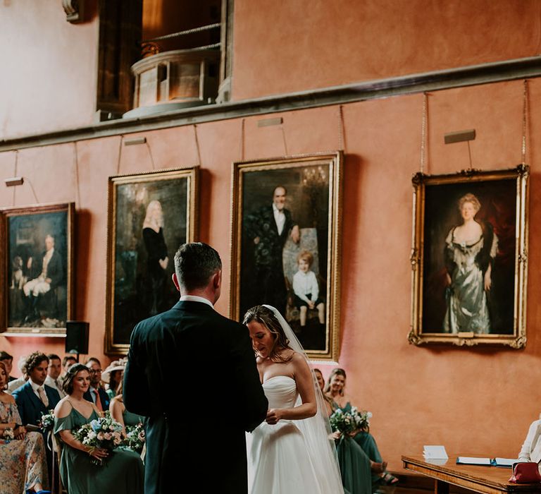 Bride & groom during wedding ceremony at Cowdray House complete with pastel florals and princess wedding dress