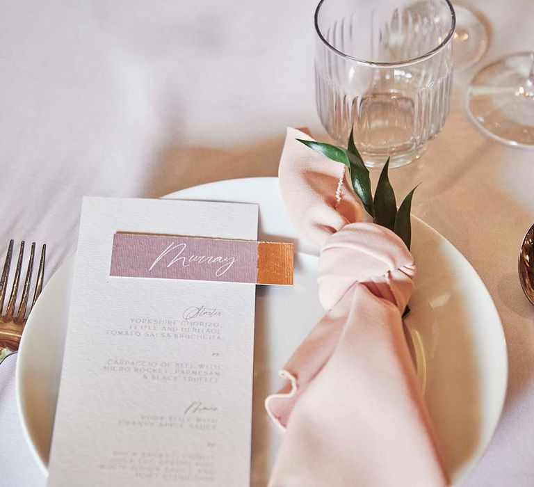 Place setting with pink napkin and menu card 