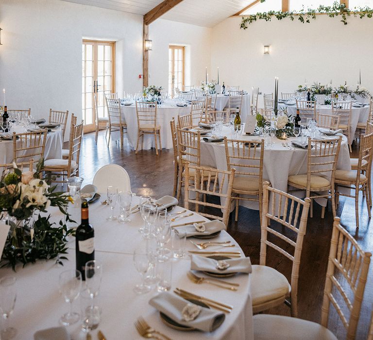 Green wedding colour scheme for the wedding reception with white flowers, taper candles and round tables 