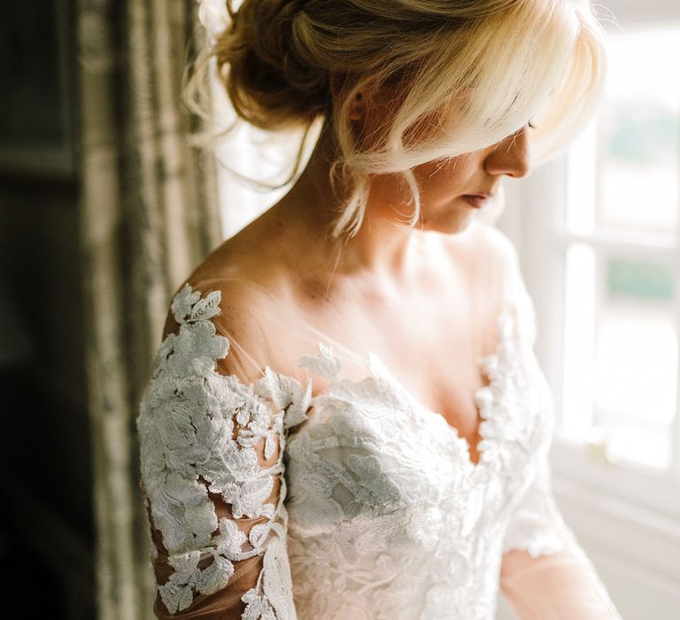 Blonde bride wears her hair in loose curled hairstyle and wears lace long sleeve Pronovias wedding dress 