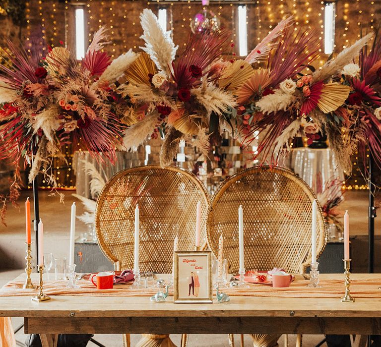 Sweetheart top table with boho peacock chairs with colourful candles and a pink flower cloud 