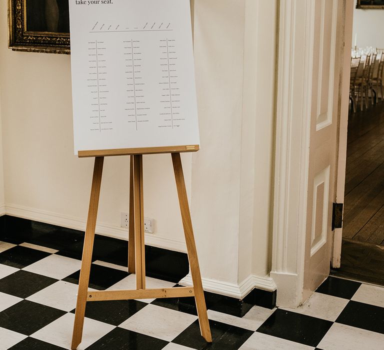 Minimalistic white seating chart on wooden easel at Kelmarsh Hall 