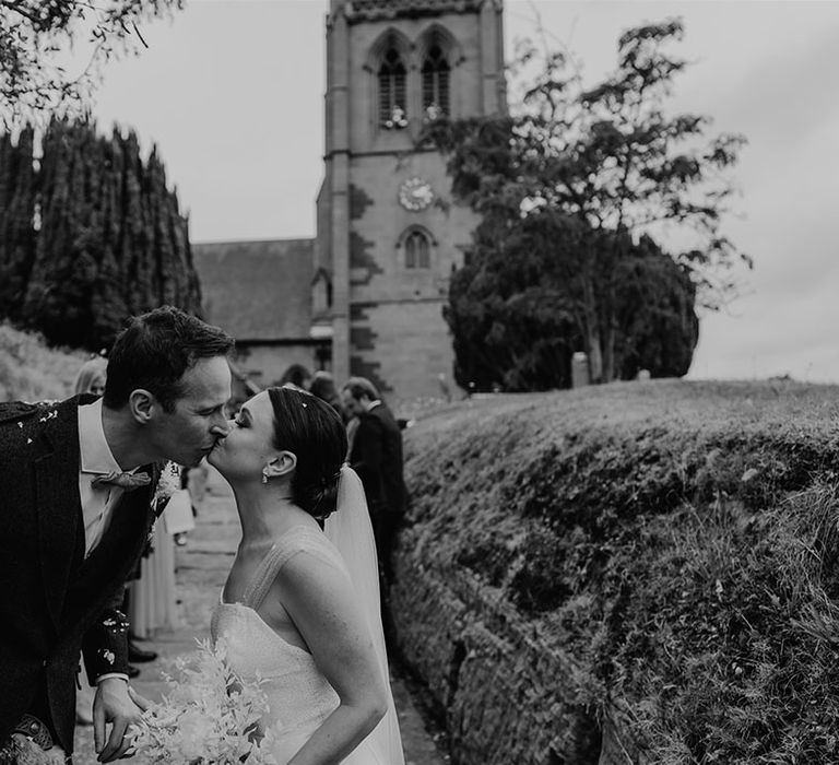 Bride and from she a kiss after their confetti exit from the church ceremony 