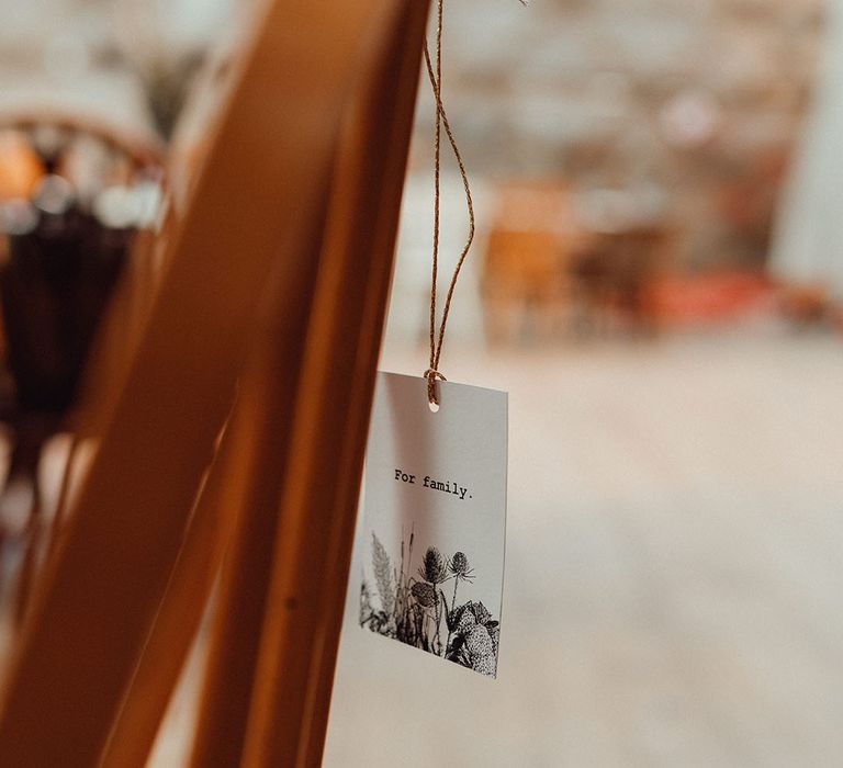 Wedding chair back decor with label tied with gold string reserving the seat for family members 