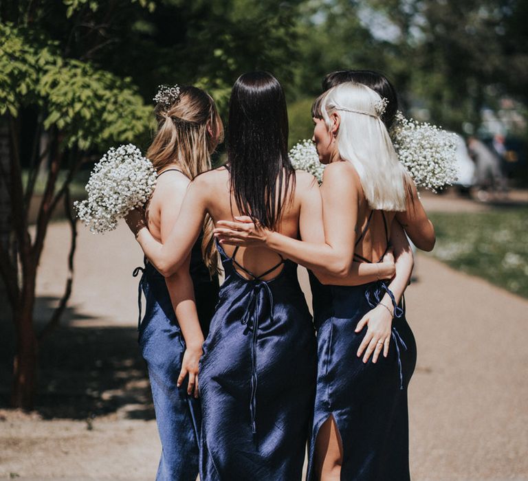 Bridesmaids wear navy midi bridesmaid dresses with low backs and tie to waist