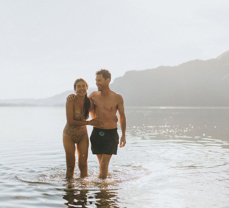 The bride and groom smile together after enjoying a morning swim in the Ullswater river before the wedding 