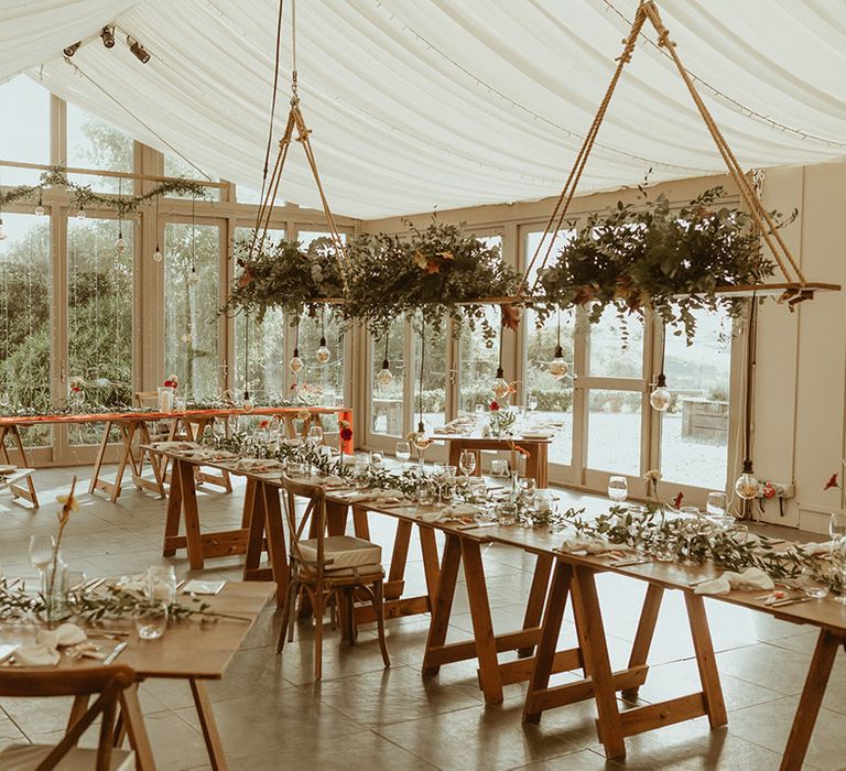 Trevenna Barns wedding venue with festoon lighting, hanging floral installations, and minimal wedding table setting 