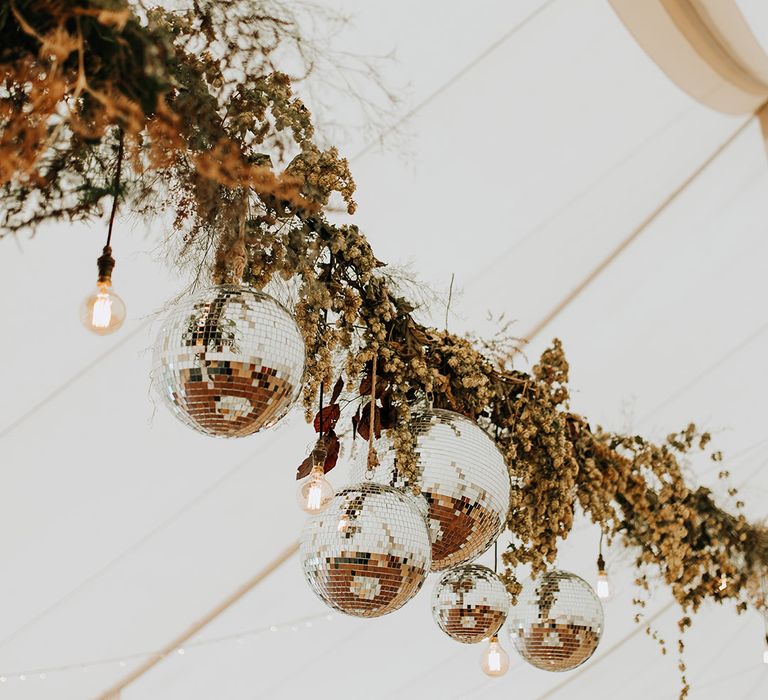 Hanging floral installation with disco ball decoration in the marquee at Duddon Mill Farm 