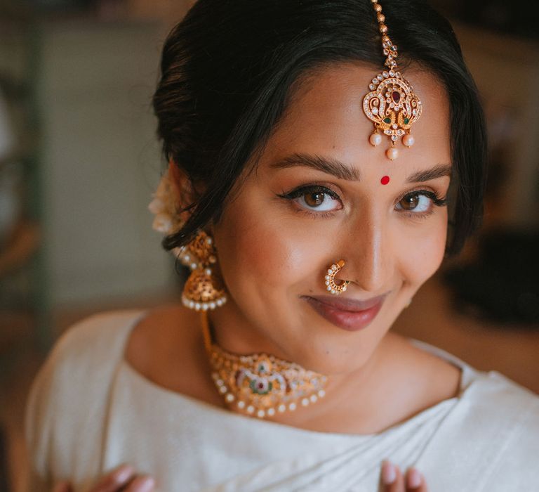 South Asian bridal makeup in a cream Lehenga and Indian gold jewellery 