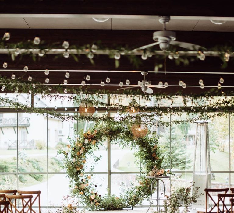 White pillar candles in different size hurricane vases with big botanical and foliage heavy floral arrangements for the indoor aisle decorations