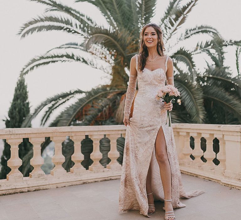 bride in a bespoke gold sparkly wedding dress with front slit and sheer long sleeves