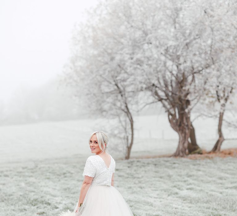 Frosty wedding day with the bride in tulle bridal skirt and beaded top with short sleeves 