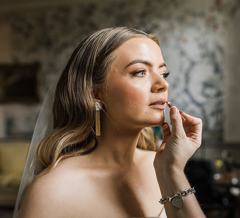 The bride gets her makeup done for her wedding day with smoky eyeliner and Hollywood wave hair style 