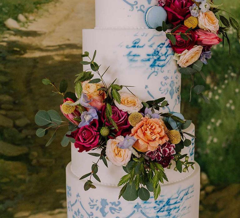 Four tiered toile wedding cake in blue and white with spring flower decorations and blue macaroons 