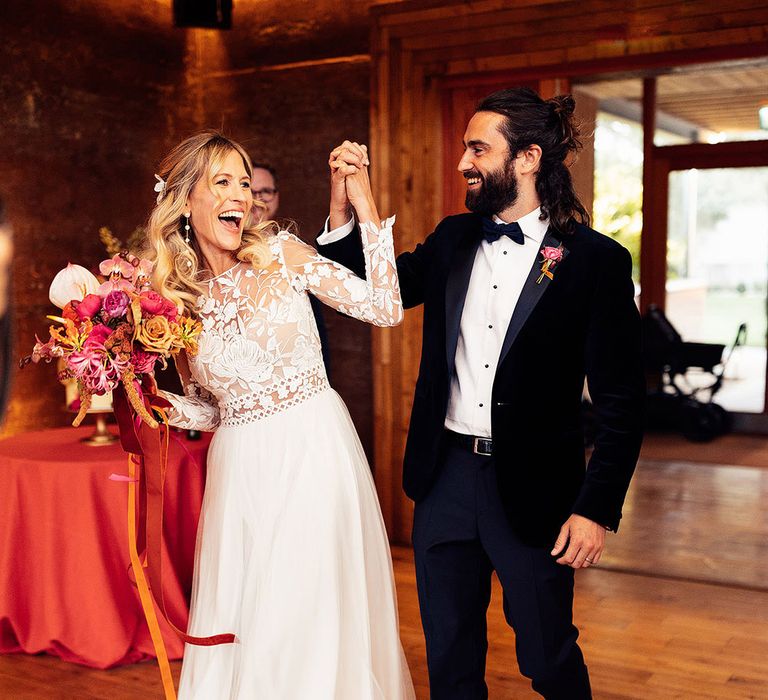 Bride walks into the wedding reception with the groom in black suit 