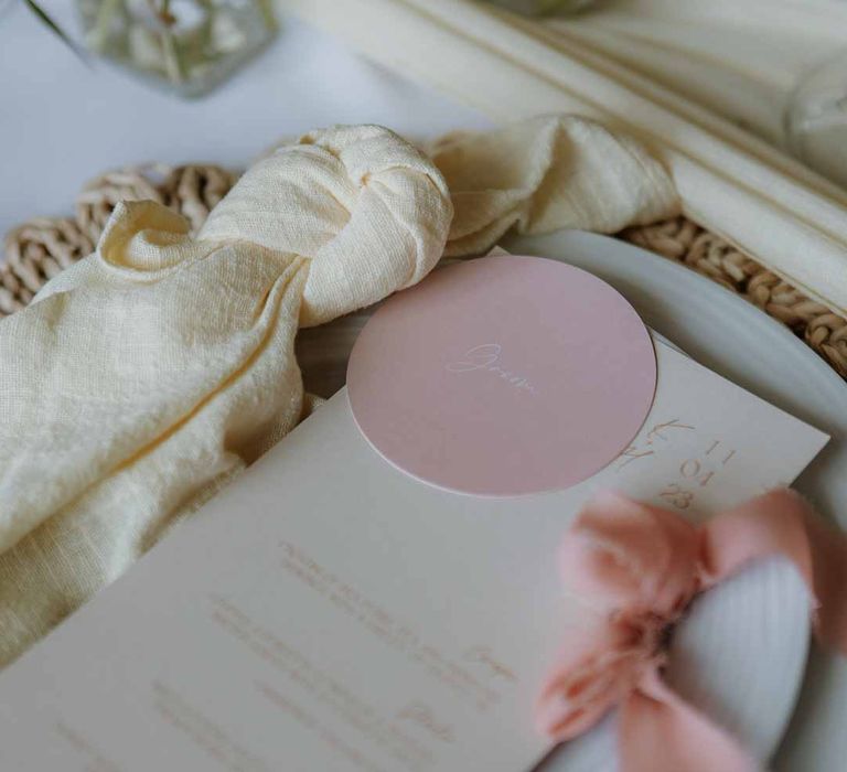 Classic white crockery on burlap wedding place mat with minimalist wedding stationery, dusky pink ribbon and yellow wedding napkins 